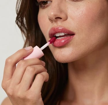 Close-up of a shiny, soft pink lip gloss tube with a subtle shimmer.