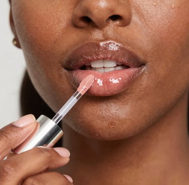 Glossy red lip gloss applied on smooth lips reflecting light.