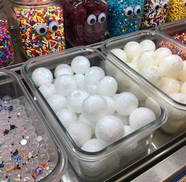A colorful tub of slime labeled 'Berry Blast' with foam beads and glitter sparkling under soft light.