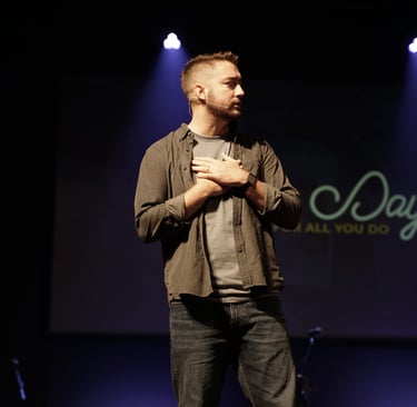 Pastor standing on stage with hands over heart.
