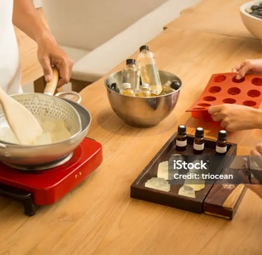 Handmade soap making workshop with essential oils, silicone molds, and melting glycerin soap base.