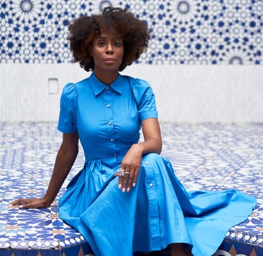 Founder of Emisha Wellness in a blue dress, red shoes in a blue & white MOR tile foyer