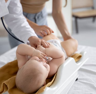 Un pediatra usa un estetoscopio para examinar a un bebé sobre una báscula digital durante un chequeo.