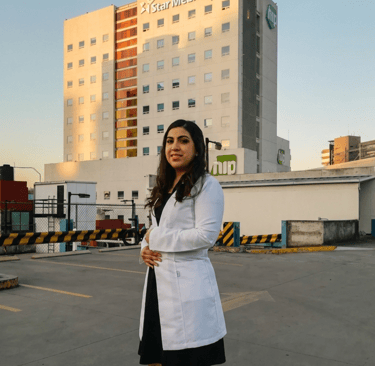 Doctora con bata blanca de pie frente al edificio del hospital Star Médica.
