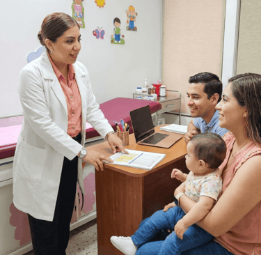 Una pediatra con bata blanca consulta con unos padres y su bebé en una clínica médica.