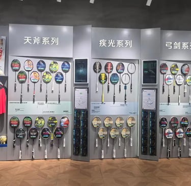 Yonex badminton rackets displayed on a store wall featuring Astrox, Nanoflare, and Arcsaber series.