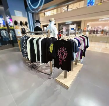 Casual graphic t-shirts and apparel on clothing racks in a modern retail fashion store.