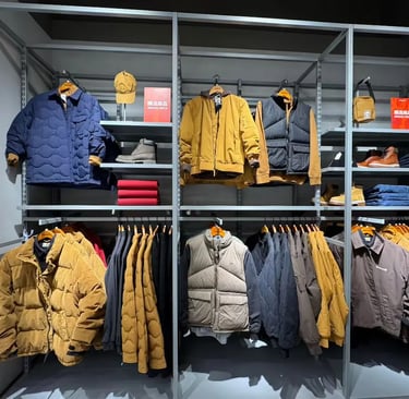 Modern retail display of Timberland winter apparel featuring puffer jackets, vests, and boots on industrial metal shelving.