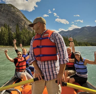 A happy group white water rafting on a mountain river wearing life jackets.