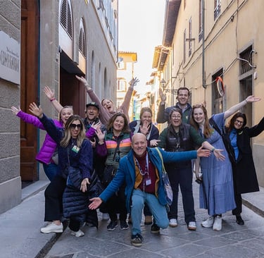 A cheerful group of tourists posing on a narrow historic street during a guided walking tour in Florence, Italy.