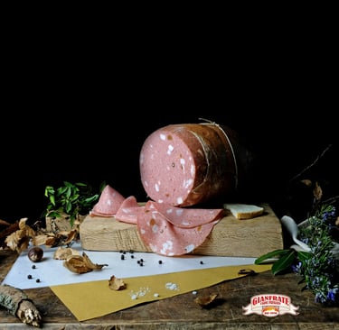 Sliced Italian mortadella deli meat on a wooden board with herbs and peppercorns on a black background.