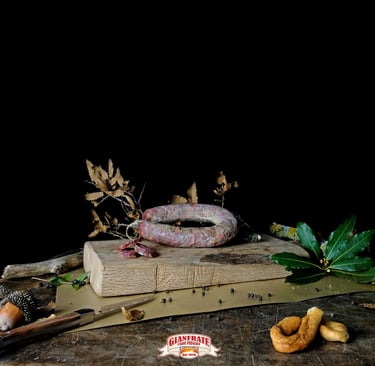 Artisanal Italian cured sausage on a rustic wooden cutting board with bay leaves and peppercorns.