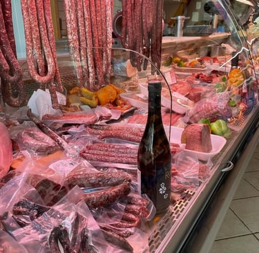 Display of cured meats, sausages, and vacuum-sealed salami at a traditional Italian butcher shop.