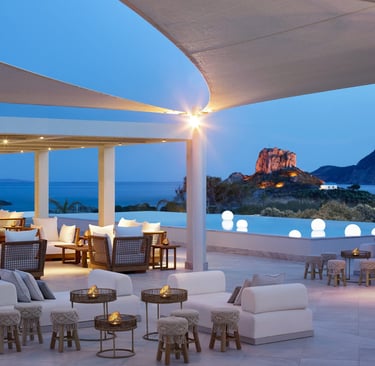 Luxury outdoor resort lounge with white sofas and ocean views at dusk near a cliffside pool.