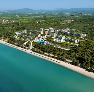 Aerial view of a luxury beachfront resort with swimming pools, turquoise sea, and lush greenery.