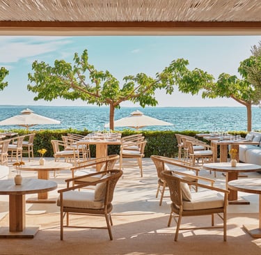 Ikos Olivia, Ouzo restaurant terrace  over looking a blue sea with green trees 