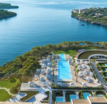 Aerial view of a luxury coastal resort in Mallorca with swimming pools and turquoise ocean views.