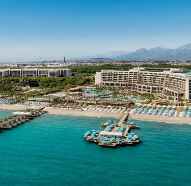 Regnum The Crown, Belek resort in Turkey with piers, blue water, and mountains.