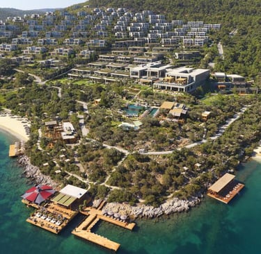 Aerial view of a luxury Aegean sea resort with modern villas, private beaches, and wooden docks in Bodrum.