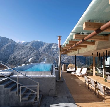 Luxury rooftop terrace with infinity pool overlooking snow-covered mountains in a winter resort.