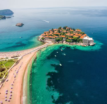 Aerial view of Sveti Stefan island resort and pink sand beach on the Adriatic coast in Montenegro.