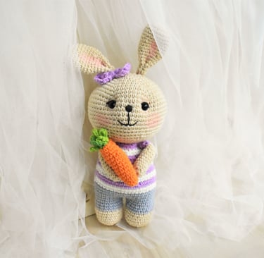 Conejo amigurumi tejido a crochet hecho a mano con camiseta morada a rayas sosteniendo una zanahoria