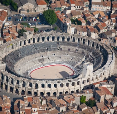 Aerial view of the ancient Roman amphitheater Arles Arena in France surrounded by historic red-roofed buildings.