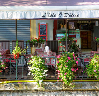 Outdoor patio at L'isle O Delice restaurant with floral decorations and red checkered tablecloths.
