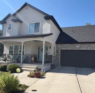 after exterior remodel house is now cream-colored stucco with natural stone veneer in light to medium gray tones.