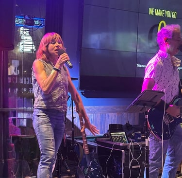 Tracy and Dan performing live music on a stage with neon lighting.