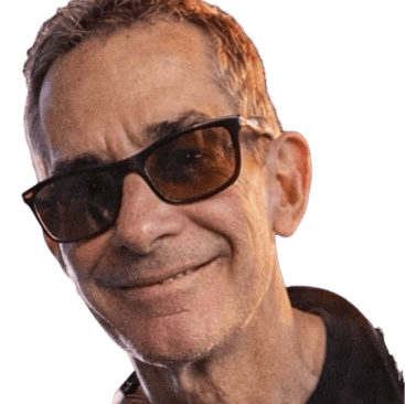 Tom wearing dark-rimmed glasses against a black background.