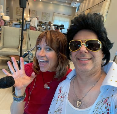 Tracy and Elvis in costume posing for a selfie at a social event.