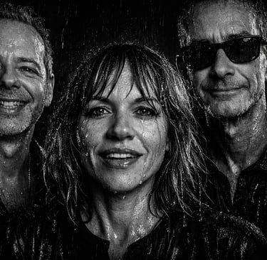 Black and white portrait of a smiling Rockadelic band standing in the pouring rain.
