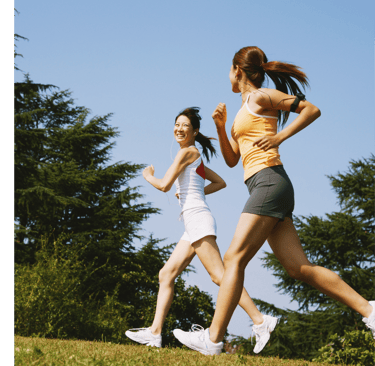 two women running in the grass with trees in the background