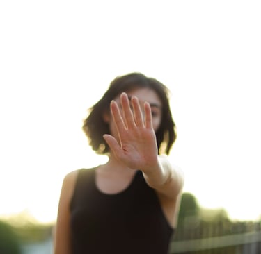 mulher jovem de cabelos escuros, imagem desfocada, mão a frente do rosto