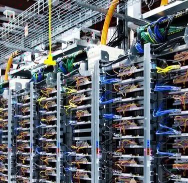 Modern AI data center with organized server racks and complex colorful network cabling.