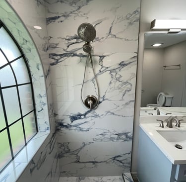 Modern bathroom featuring marble-patterned wall tiles, a rainfall showerhead, and a matching hexagon floor.
