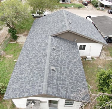 Aerial view of a residential house featuring newly installed gray architectural asphalt roof shingles.