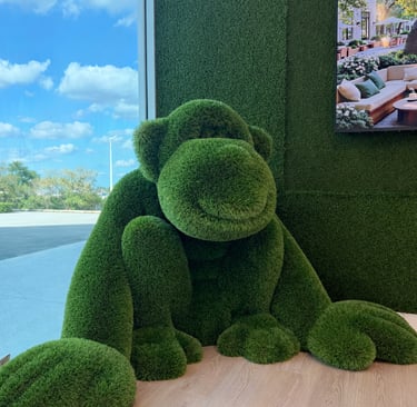 Large custom artificial turf sculpture shaped like a sitting monkey displayed indoors.