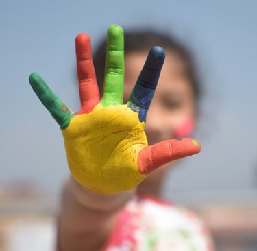 Child’s hand covered in colorful paint.