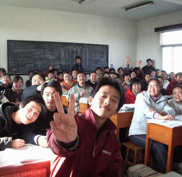classroom of students, smiling, one is giving a peace sign