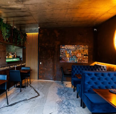 Interior do Okone Sushi Nikkei no Porto com sofás azuis, balcão de madeira, iluminação suave e decoração com plantas