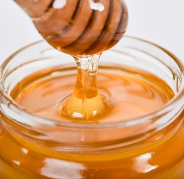 Jar of Manuka honey on a clean, minimalist kitchen counter with a wooden honey dipper.