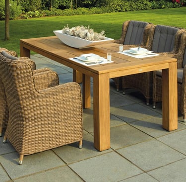 Outdoor patio dining area featuring a wooden table set with white plates and glasses