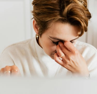 Tired woman rubbing her eyes while suffering from eye strain and headache at work.