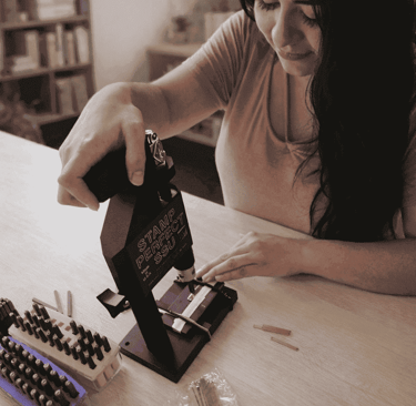 Una mujer utiliza una herramienta de estampado de metal para grabar joyas personalizada