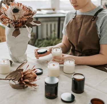 mujer trabajando con velas de cera de soya aromaticas, acomodandolas y tapandolas