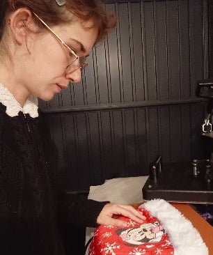 A woman customizes a Christmas Santa hat with a heat press, ideal for holiday gifts and personalized apparel.