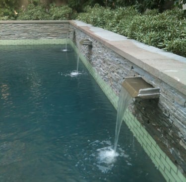 a pool with three custom stone spillways
