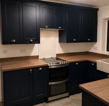 Navy shaker-style kitchen cabinets with brass handles, wood-effect countertops, an electric cooker.